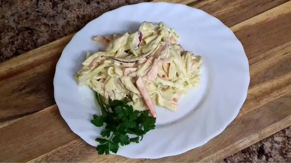 Finished coleslaw served on a plate with parsley garnish.
