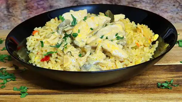 Chicken Stroganoff served over colorful vegetable rice in a black bowl, garnished with fresh parsley.
