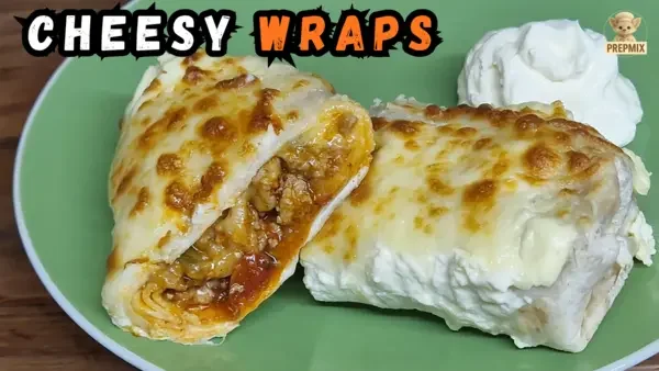 Cheesy baked tortilla wraps filled with seasoned minced pork, topped with golden melted cheese and served with sour cream on a green plate.